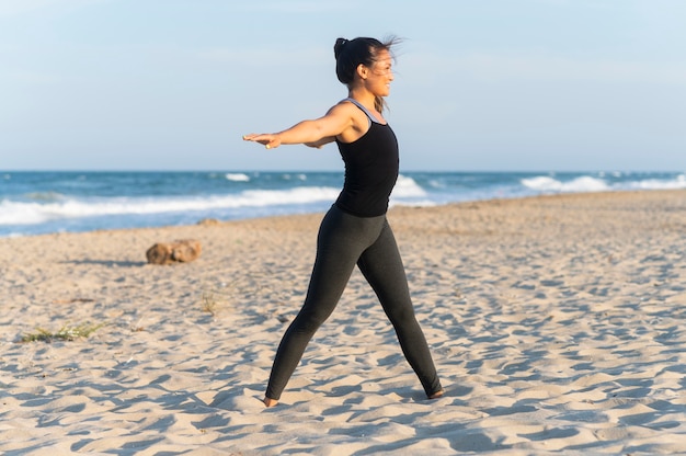 Foto gratuita vista lateral de la mujer haciendo fitness en la playa