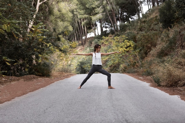 Vista lateral de la mujer haciendo yoga en la carretera