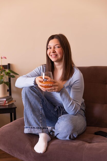 La vista lateral de una mujer hermosa mirando la cámara y relajándose en casa