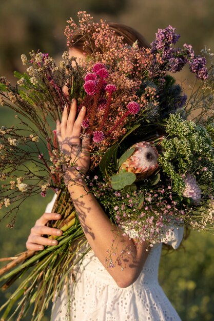 Vista lateral mujer con hermoso ramo de flores