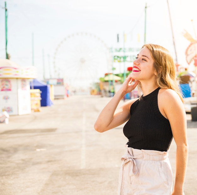 Vista lateral de la mujer joven feliz que goza en el parque de atracciones