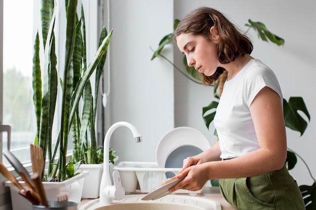 Vista lateral, mujer joven, lavar platos