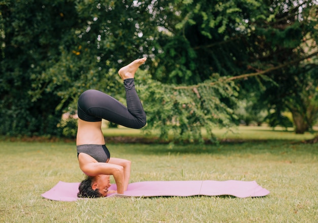 Vista lateral de una mujer joven practicando yoga en el parque