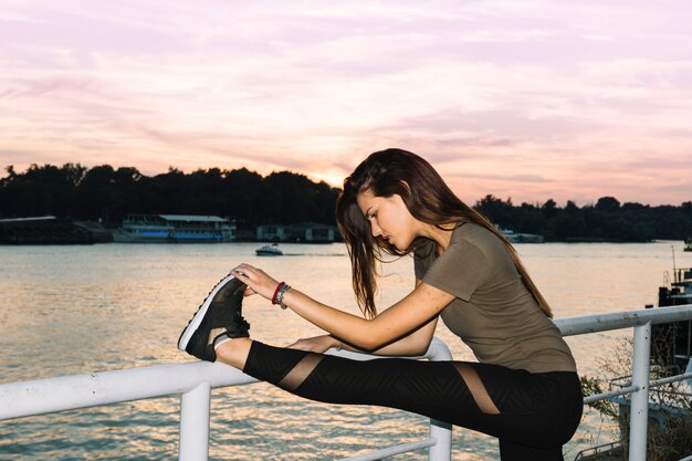 Vista lateral de una mujer joven que estira su pierna