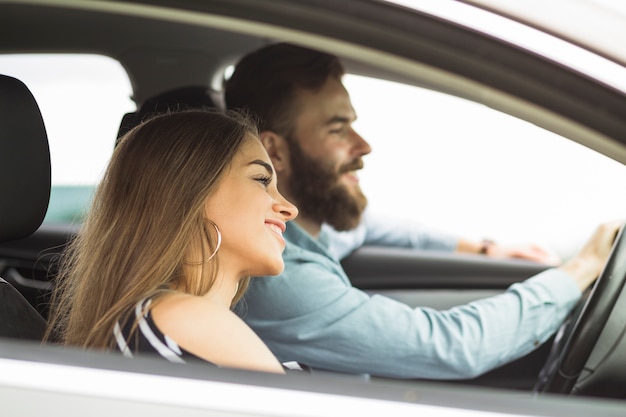 Vista lateral de una mujer joven con su novio viajando en el coche