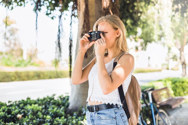 Vista lateral de una mujer joven tomando fotos al aire libre