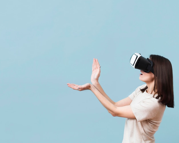 Vista lateral de la mujer jugando mientras usa casco de realidad virtual con espacio de copia