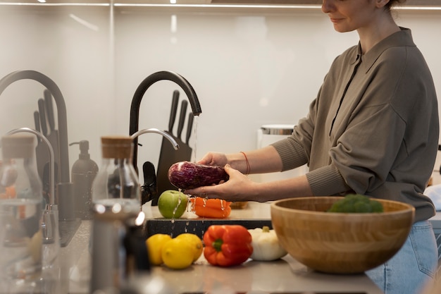 Foto gratuita vista lateral mujer lavando verduras