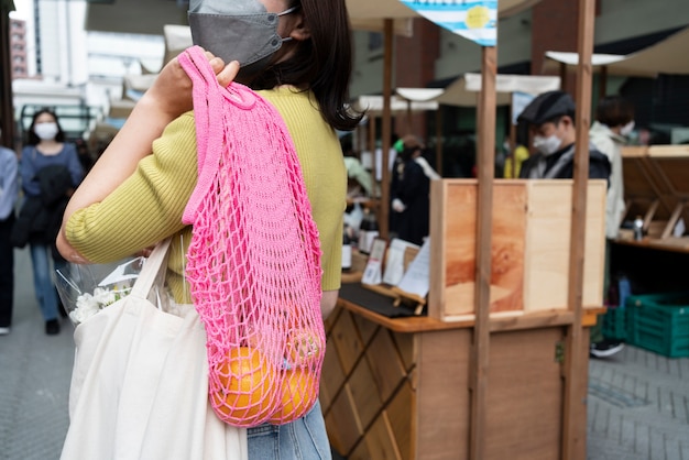 Vista lateral mujer llevando comestibles en bolso de mano