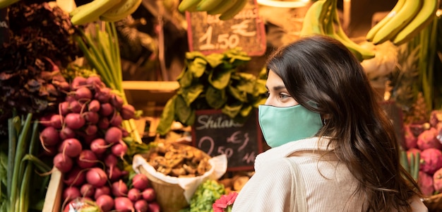 Foto gratuita vista lateral de la mujer con mascarilla en el mercado