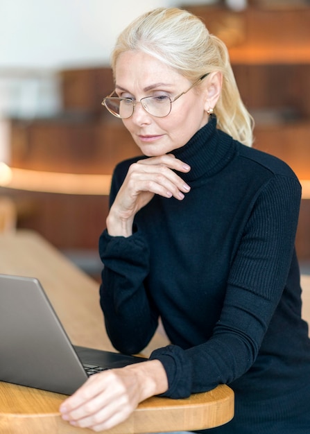 Foto gratuita vista lateral de la mujer mayor con gafas y trabajando en equipo portátil