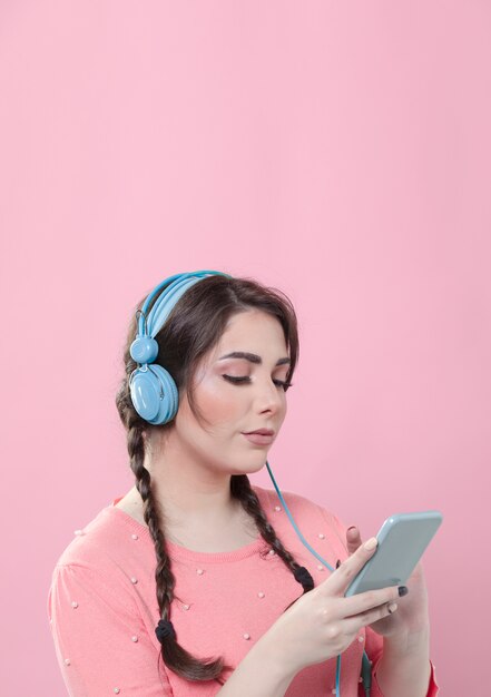 Vista lateral de la mujer mirando el teléfono inteligente mientras usa auriculares