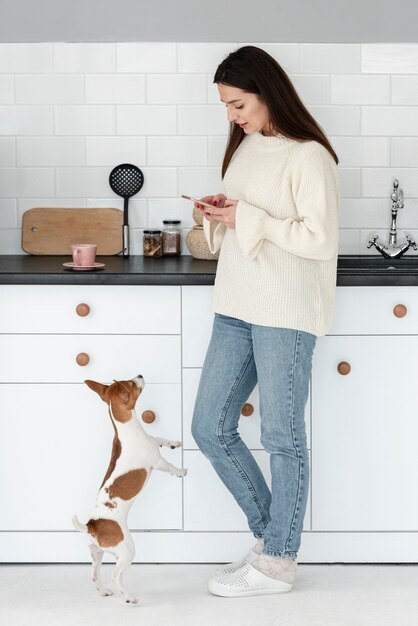 Vista lateral de la mujer mirando el teléfono inteligente con perro