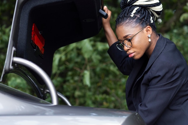 Foto gratuita vista lateral de la mujer mirando a través del maletero de su coche