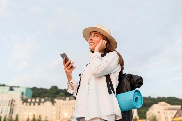 Vista lateral de la mujer con mochila y smartphone viajando