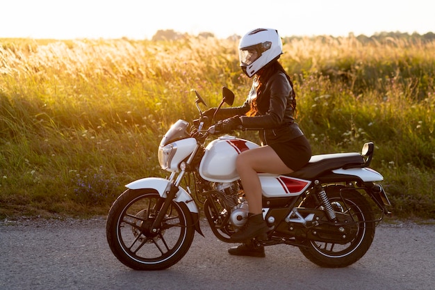 Vista lateral de la mujer montando motocicleta con casco