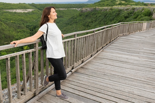 Foto gratuita vista lateral de la mujer en la naturaleza posando en el puente