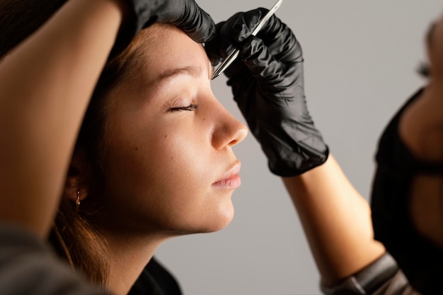 Vista lateral de la mujer obteniendo sus cejas por especialista