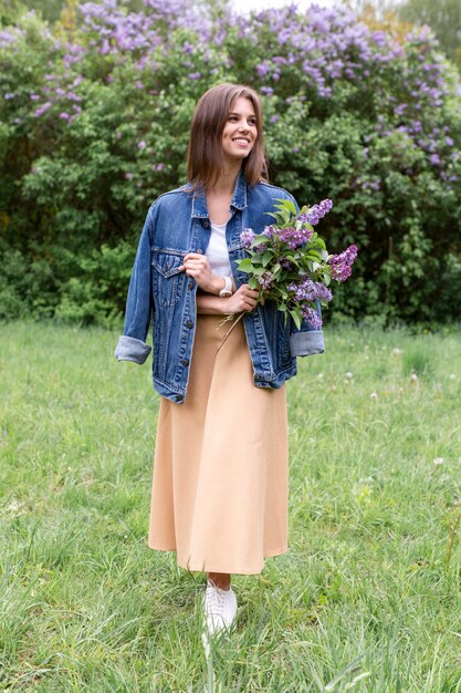 Vista lateral mujer en parque con flores lilas