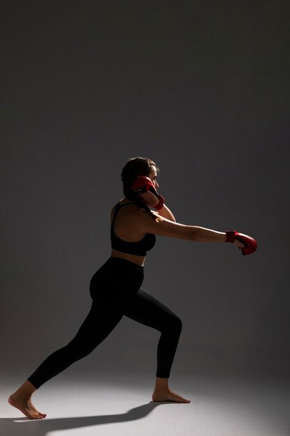Vista lateral de mujer perforando con guantes de box