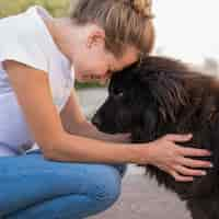 Foto gratuita vista lateral de la mujer con perro negro esponjoso al aire libre