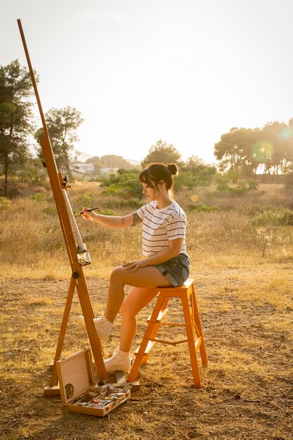 Foto gratuita vista lateral de la mujer pintando sobre lienzo al aire libre