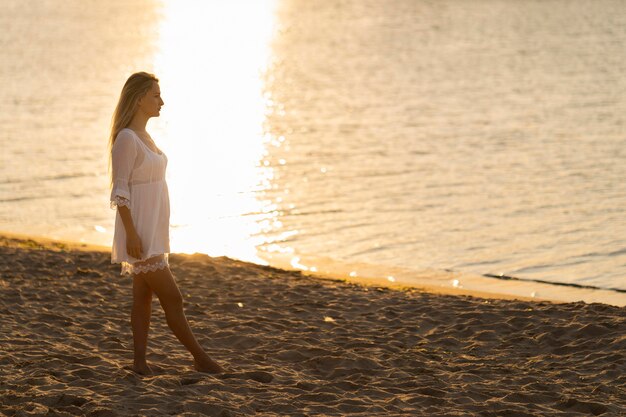 Vista lateral de la mujer en la playa al atardecer