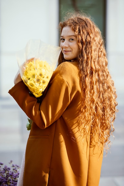 Foto gratuita vista lateral de la mujer posando al aire libre con ramo de flores de primavera