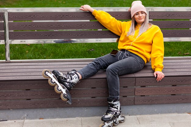 Vista lateral de la mujer posando en un banco con patines