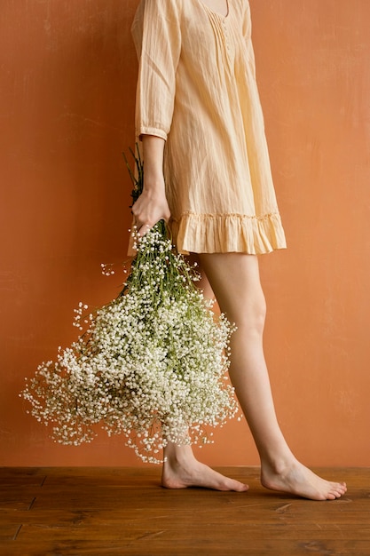 Vista lateral de la mujer posando mientras sostiene ramo de flores de primavera