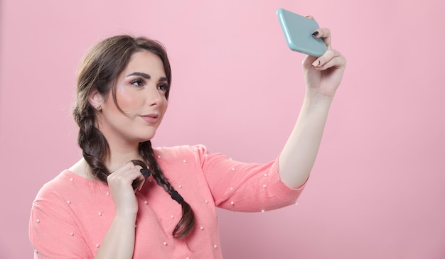 Foto gratuita vista lateral de la mujer posando para una selfie mientras sostiene el teléfono inteligente