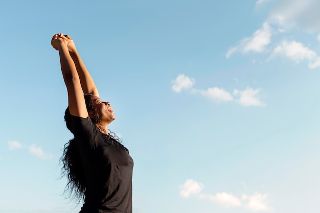 Vista lateral de la mujer que se extiende con espacio de copia y cielo despejado