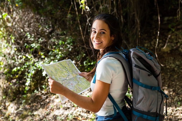 Vista lateral de la mujer que intenta explorar la naturaleza mientras usa el mapa