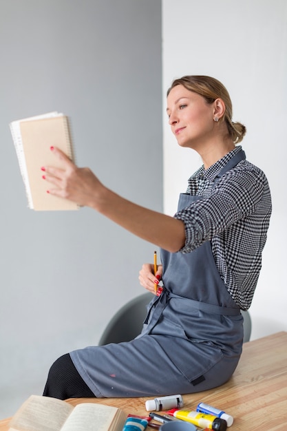 Foto gratuita vista lateral de la mujer que sostiene el cuaderno