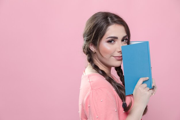 Vista lateral de la mujer que sostiene el libro cerca de la cara