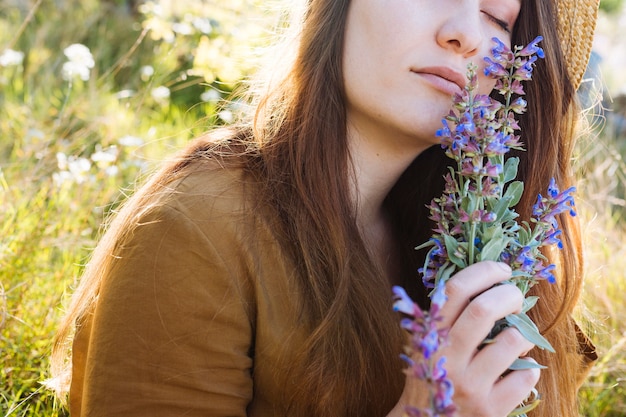 Foto gratuita vista lateral, de, mujer que sostiene y que huele, ramo de flores