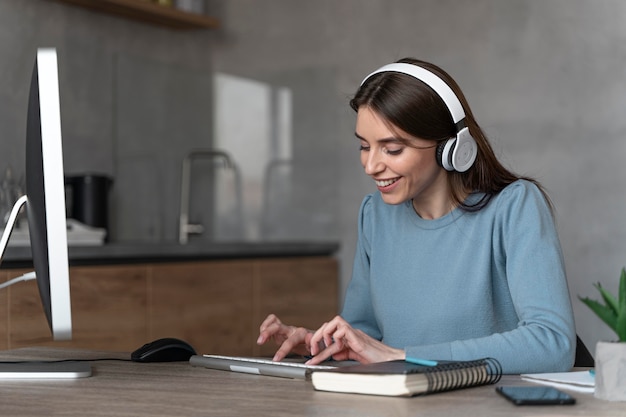 Foto gratuita vista lateral de la mujer que trabaja en el campo de los medios con computadora y auriculares