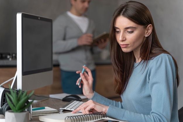 Vista lateral de la mujer que trabaja en el campo de los medios de comunicación con computadora personal