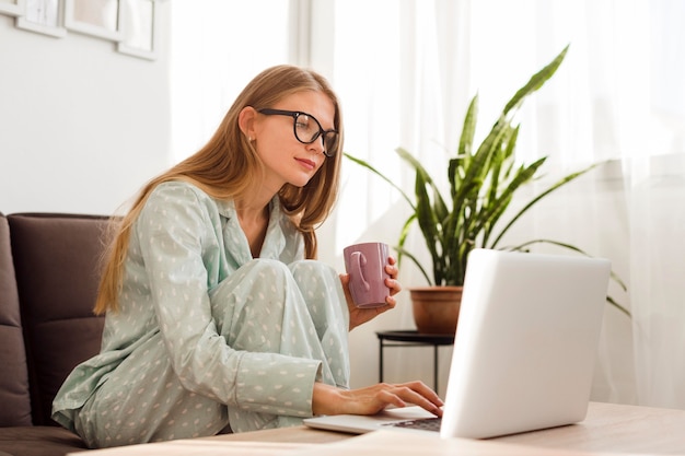 Vista lateral de la mujer que trabaja en la computadora portátil desde casa