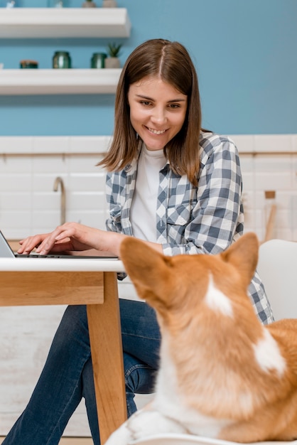 Vista lateral de la mujer que trabaja en la computadora portátil con su perro