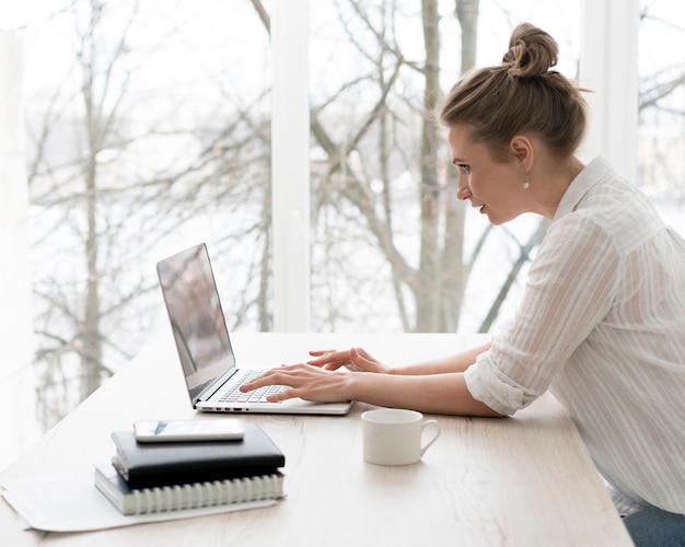 Foto gratuita vista lateral mujer que trabaja en la computadora portátil