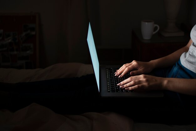 Vista lateral de la mujer que trabaja tarde en casa en la computadora portátil