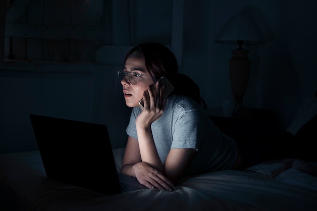 Vista lateral de la mujer que trabaja hasta tarde mientras habla por teléfono