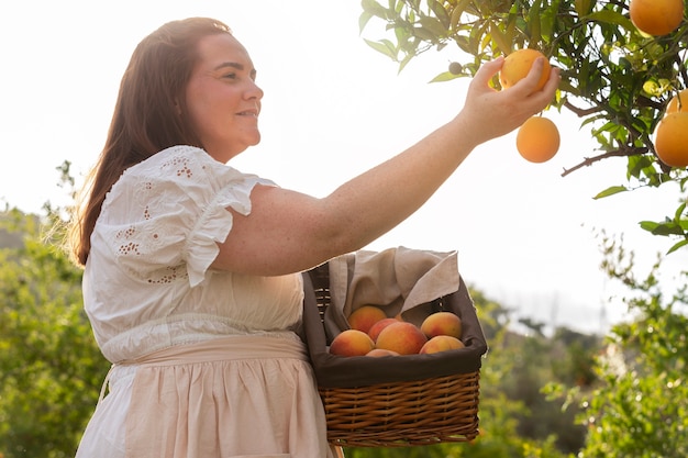 Vista lateral mujer recogiendo frutas