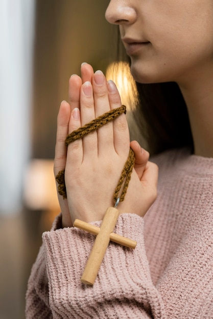 Vista lateral de la mujer rezando con cruz de madera