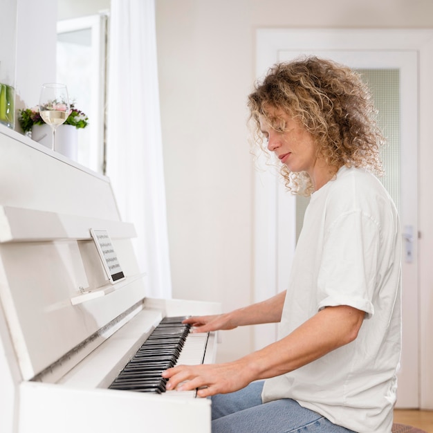 Vista lateral de una mujer rubia tocando el piano