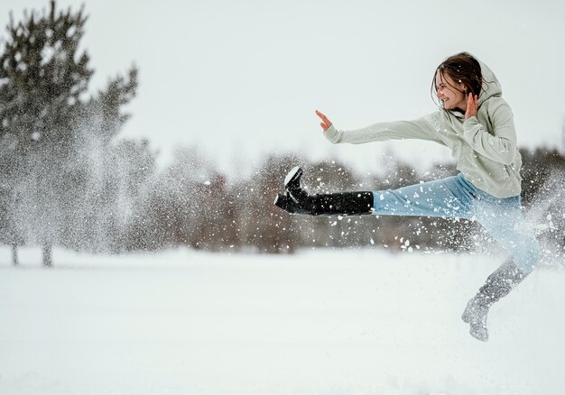 Vista lateral de la mujer saltando al aire libre en invierno