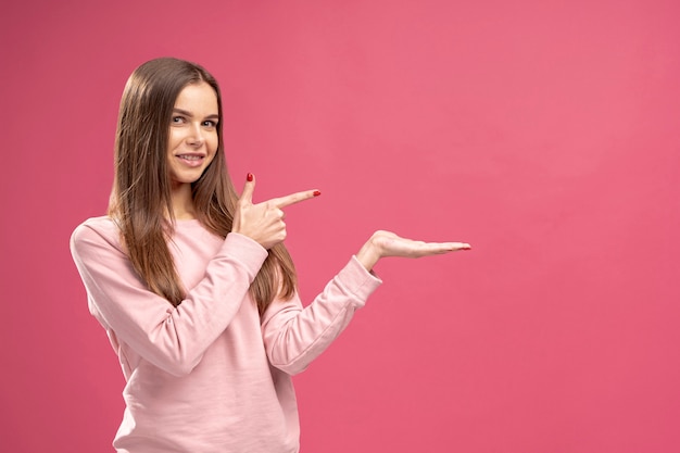 Vista lateral de la mujer señalando algo que está sosteniendo con espacio de copia