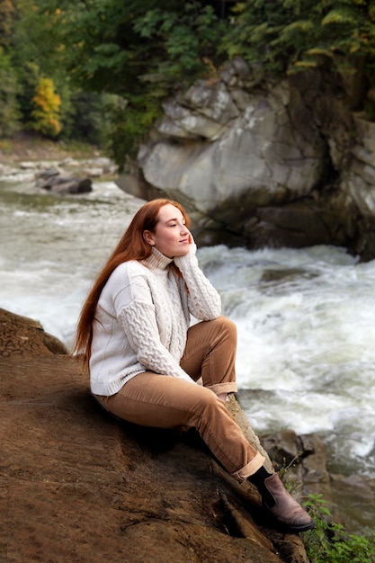 Foto gratuita vista lateral mujer sentada junto al río