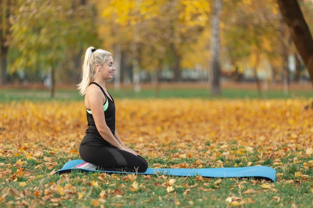 Vista lateral mujer sentada sobre una alfombra de yoga